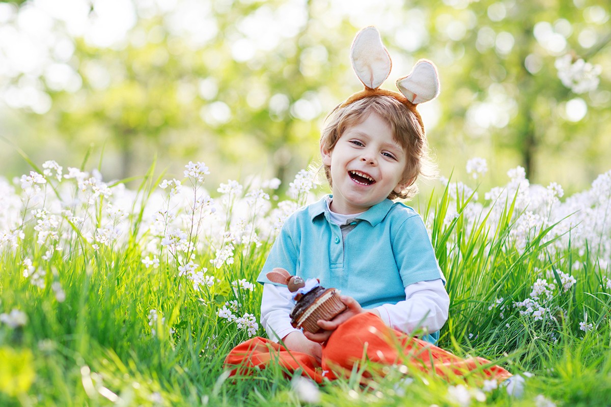 child sitting in grass wearing easter bunny ears